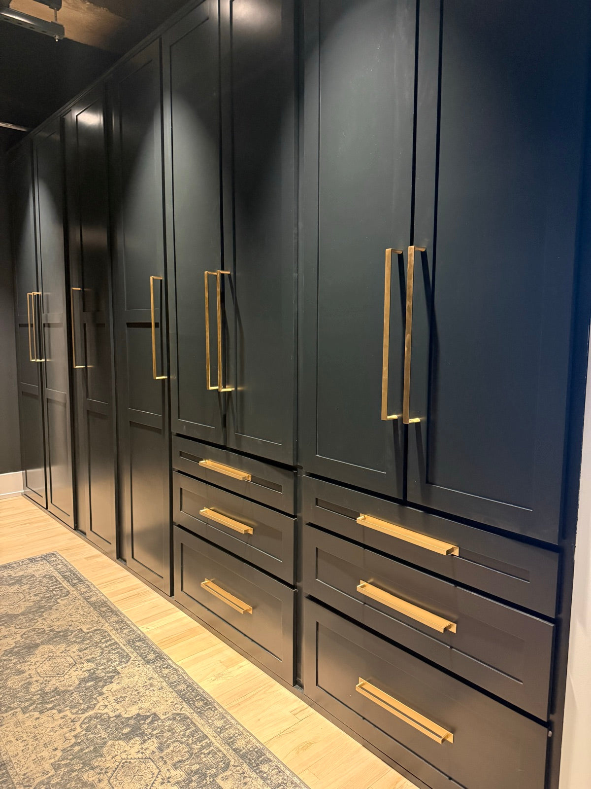 Custom black wardrobe wall with long brass bar pulls