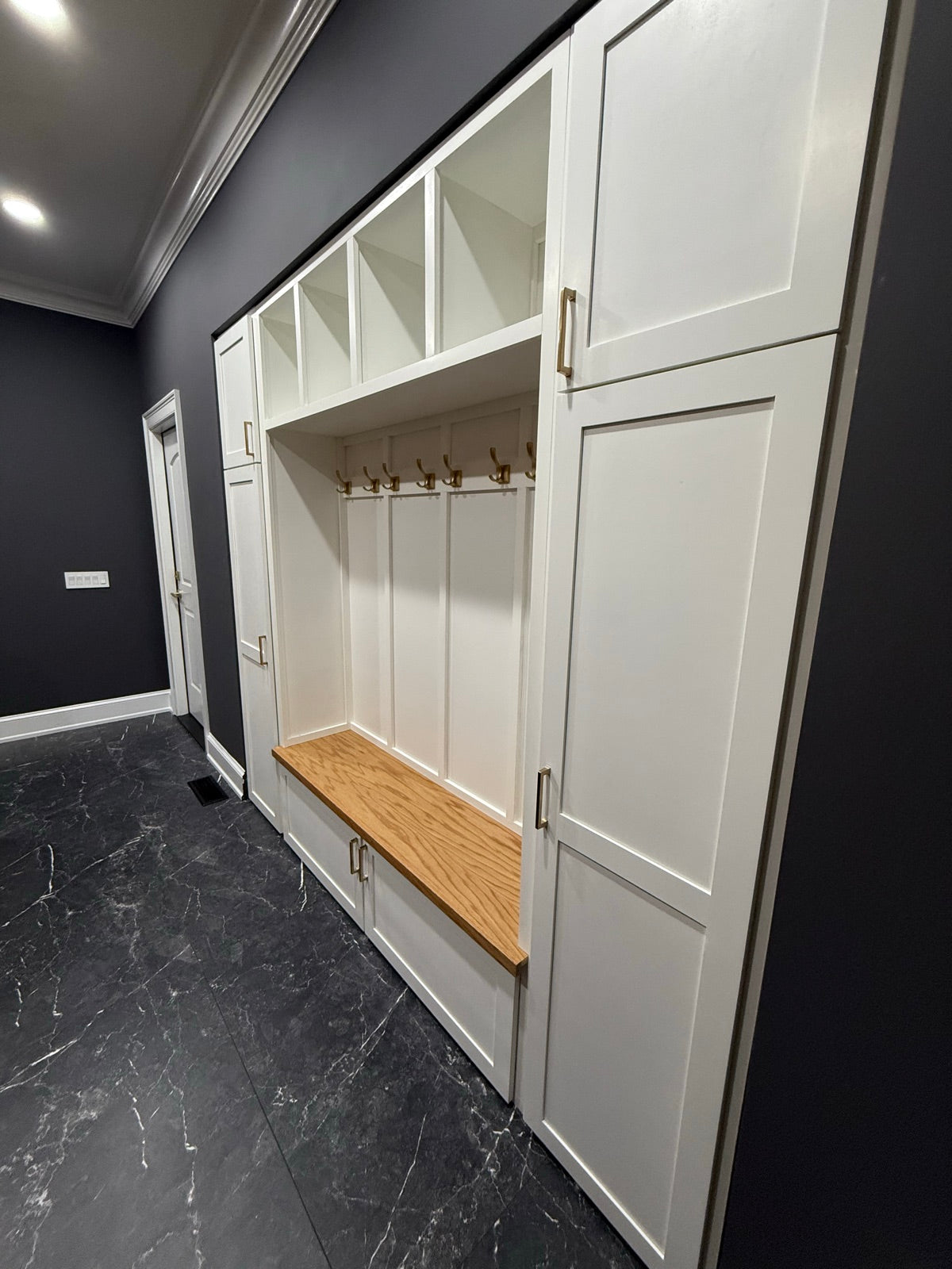 Custom white mudroom with lockers and an oak bench installed in a client's home