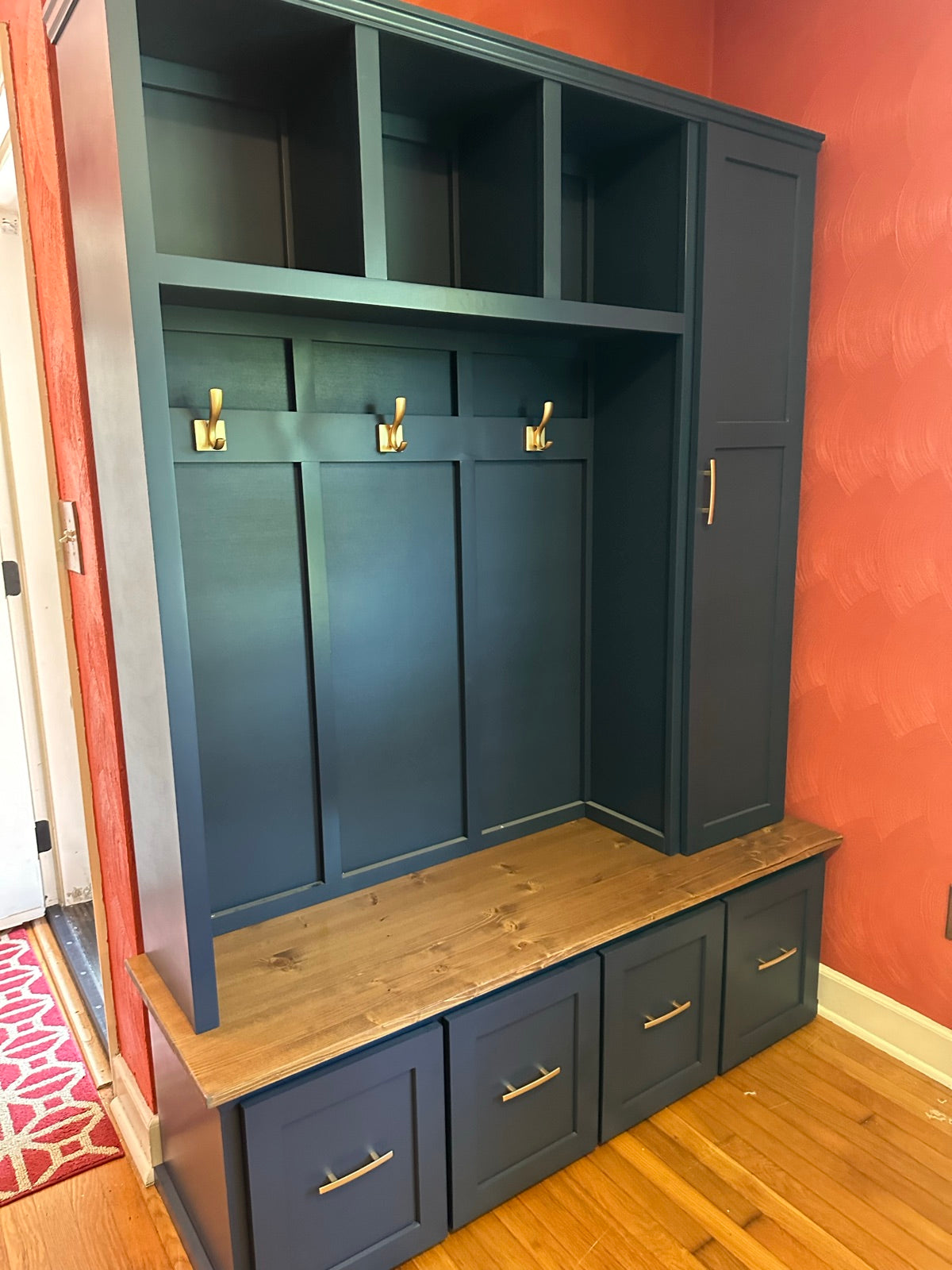 Deep teal halltree with brass hooks and a stained pine bench